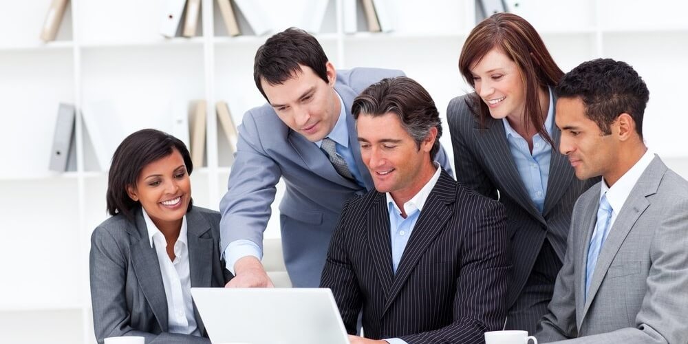 Multi-cultural business team looking at a laptop in the office-1-095173-edited